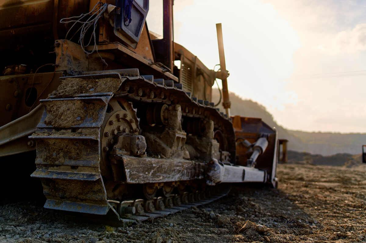 Bulldozer parked in the sun on a dirt field after project completion or fleet downsizing