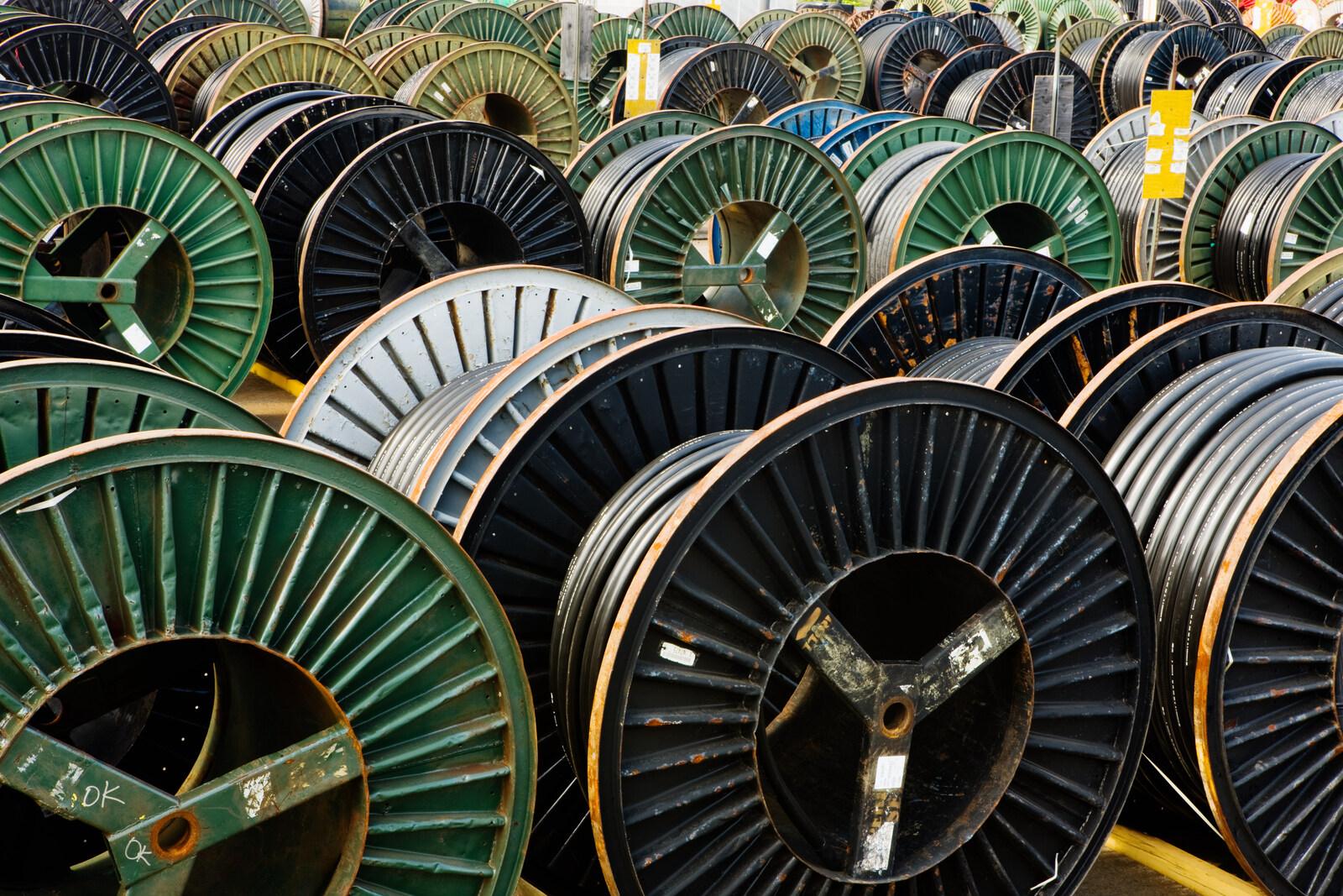Cable drums lined up in a row as surplus electrical wire inventory ready for liquidation or resale