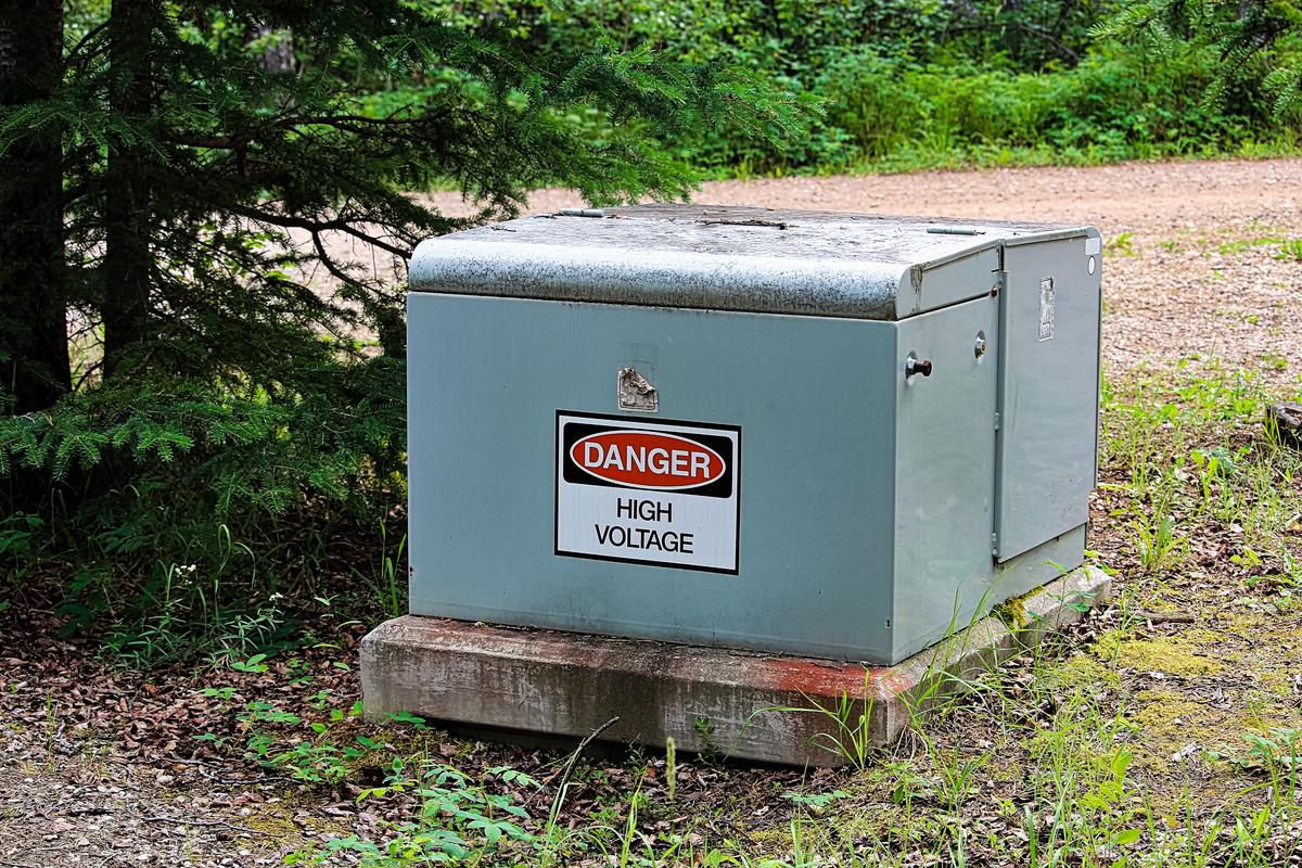 High voltage power box in a field representing utility switchgear or distribution equipment removed during upgrades
