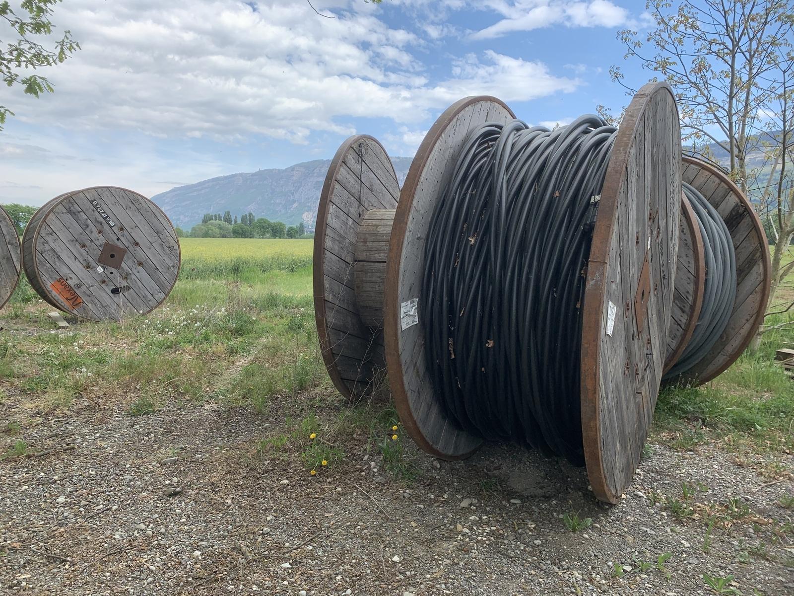 Large electrical wire cables staged in a field as part of a utility or industrial power project